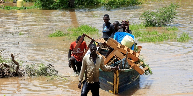 Residents use a boat to carry their belongings through the waters after their homes were flooded as the River Nzoia burst its banks and due to heavy rainfall and the backflow from Lake Victoria, in Budalangi within Busia County, Kenya May 3, 2020.