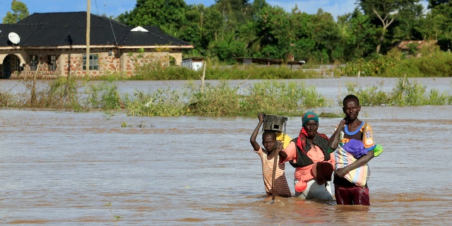 Residents wade through the waters after their home was flooded after the River Nzoia burst its banks and due to heavy rainfall and the backflow from Lake Victoria, in Budalangi within Busia County, Kenya May 3, 2020.