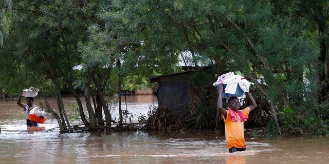 Residents carry their belongings inside flood water as they evacuate from their home after River Nzoia burst its banks and due to the backflow from Lake Victoria, in Nyadorera, Siaya County, Kenya May 2, 2020.