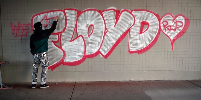 A protester spray paints George Floyd's name Friday, May 29, 2020, in Minneapolis. (Associated Press)