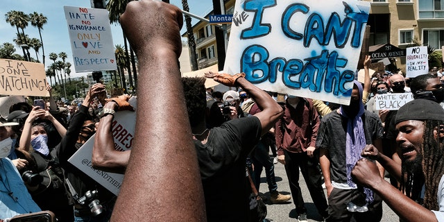 Protesters chant and raise their fists while blocking traffic on a street corner in Santa Monica, Calif., Sunday, May 31, 2020, over the death of George Floyd, a black man who died May 25 after he was pinned at the neck by a Minneapolis police officer.
