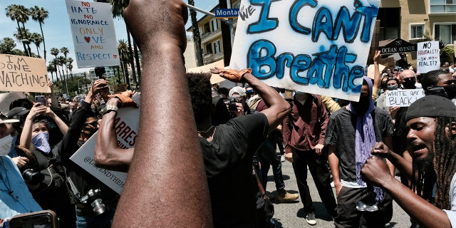 Protesters chant and raise their fists while blocking traffic on a street corner in Santa Monica, Calif., Sunday, May 31, 2020, over the death of George Floyd, a black man who died May 25 after he was pinned at the neck by a Minneapolis police officer.