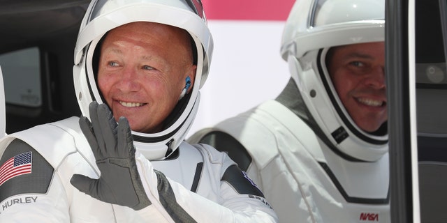 NASA astronauts Bob Behnken (R) and Doug Hurley sit in a Tesla vehicle after walking out of the Operations and Checkout Building on their way to the SpaceX Falcon 9 rocket with the Crew Dragon spacecraft on launch pad 39A at the Kennedy Space Center on May 30, 2020 in Cape Canaveral, Florida.