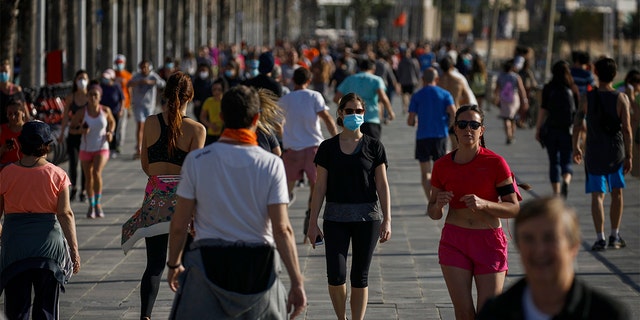 People exercises in a seafront promenade in this photo taken with a telephoto lens in Barcelona, Spain, Saturday, May 2, 2020. Spaniards have filled the streets of the country to do exercise for the first time after seven weeks of confinement in their homes to fight the coronavirus pandemic. People ran, walked, or rode bicycles under a brilliant sunny sky in Barcelona on Saturday, where many flocked to the maritime promenade to get as close as possible to the still off-limits beach. (AP Photo/Emilio Morenatti)