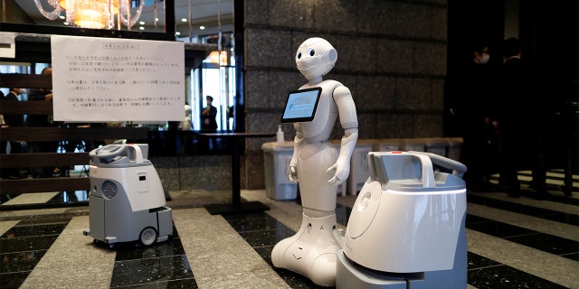 A Pepper humanoid robot, manufactured by SoftBank Group Corp. and cleaning robot Whiz are seen during a press preview at a hotel of APA Group that has been designated to accommodate asymptomatic people and those with light symptoms of the coronavirus disease (COVID-19) to free up hospital beds and alleviate work by nurses and staff members, in Tokyo, Japan May 1, 2020.