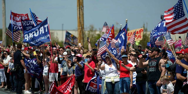 A crowd of people look on as the motorcade carrying President Trump passes on the way to a tour of Owens & Minor Inc., a medical supply company, Thursday, May 14, 2020, in Allentown, Pa. (AP Photo/Evan Vucci)