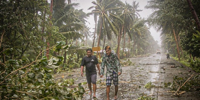 Residents brave rains and strong wind as they walk past uprooted trees along a highway in Can-avid town, Eastern Samar province, central Philippines on May 14, as Typhoon Vongfong makes landfall.