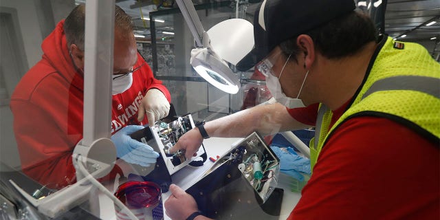 Ford Motor Co., team leader Kyle Lenart, right, inspects a ventilator that the automaker is assembling at the Ford Rawsonville plant, Wednesday, May 13, 2020 in Ypsilanti Township, Mich. The plant was converted into a ventilator factory, as hospitals battling the coronavirus report shortages of the life-saving devices. The company has promised to deliver 50,000 by July 4. Lenart is volunteering to make ventilators at the plant outside Detroit that, beginning Monday, will phase back into producing automotive components. (AP Photo/Carlos Osorio)