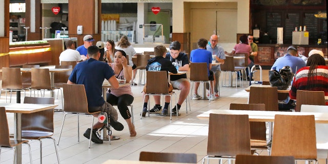 People eat in the food court at Penn Square Mall as the mall reopens Friday, May 1, 2020, in Oklahoma City. The tables in the food court have been thinned out, reducing capacity from from 600 to 170 seats.