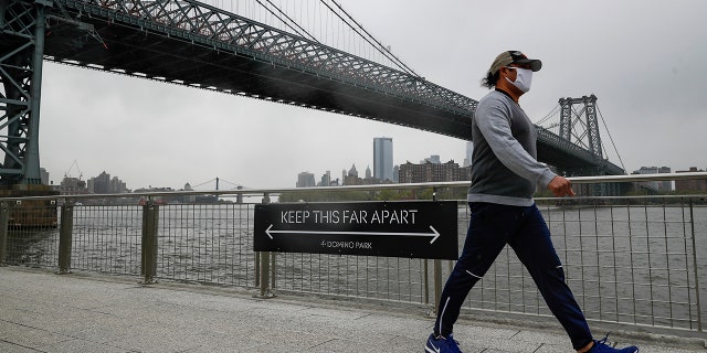 A visitor wearing a protective mask walks through Domino Park in the Brooklyn borough of New York in May. (AP Photo/John Minchillo)