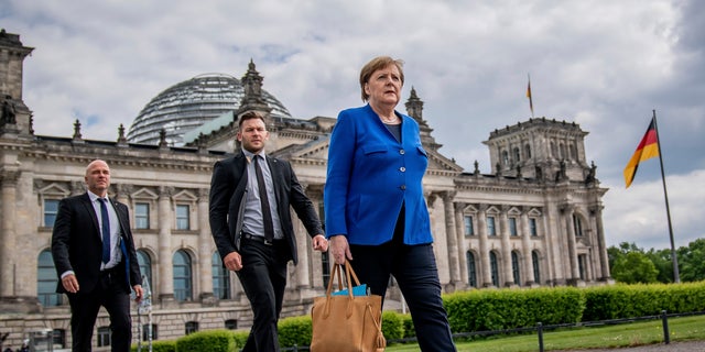 German Chancellor Angela Merkel (CDU) walks on foot, accompanied by her bodyguards, after government questioning in parliament in Berlin on Wednesday. (AP)
