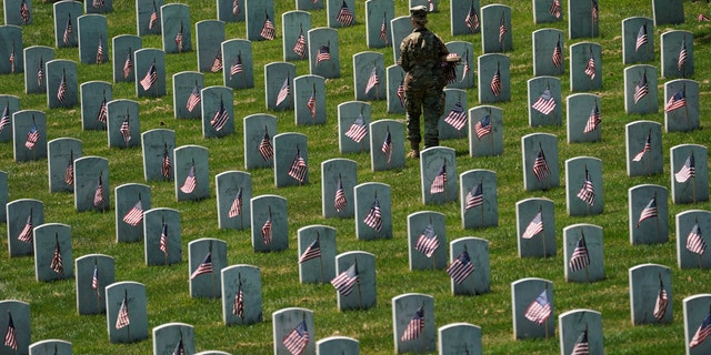 An Old Guard takes part in Flags-In, an annual event where a small American flag is placed in front of more than 240,000 headstones of U.S. service members buried at Arlington National Cemetery in Arlington, Virginia, U.S., May 23, 2019. (REUTERS/Kevin Lamarque)