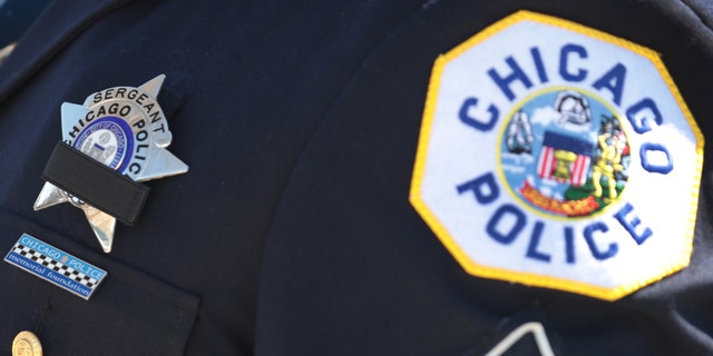 A police officer wears a button with a picture of Sgt. Clifford Martin, a 25-year veteran of the Chicago Police Department, while attending his funeral on April 21 in Chicago. Martin died on April 10, from complications from COVID-19. In accordance with the social distancing restrictions imposed by the state, only 10 family members were allowed inside the funeral home for the service and police officers joining in the procession were asked to remain in their cars outside of the funeral home during the service. (Photo by Scott Olson/Getty Images)