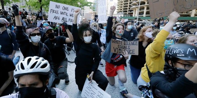 People get down on their knee during a protest over the death of George Floyd in Chicago, Saturday, May 30, 2020.