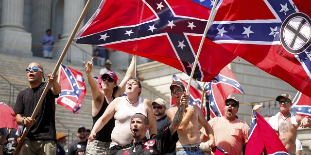 Members of the Ku Klux Klan yell as they fly Confederate flags during a rally at the statehouse in Columbia, South Carolina July 18, 2015. A Ku Klux Klan chapter and an African-American group planned overlapping demonstrations on Saturday outside the South Carolina State House, where state officials removed the Confederate battle flag last week. REUTERS/Chris Keane? TPX IMAGES OF THE DAY - GF10000163673