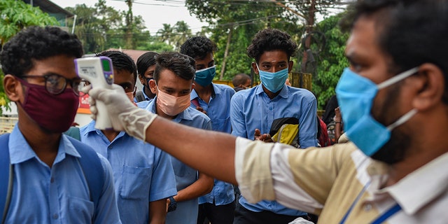 School children wearing masks get their hands sanitized and temperatures checked as they arrive to appear for state board examination during the coronavirus pandemic in Kochi, Kerala state, India, Tuesday, May 26, 2020. (AP Photo/R S Iyer)