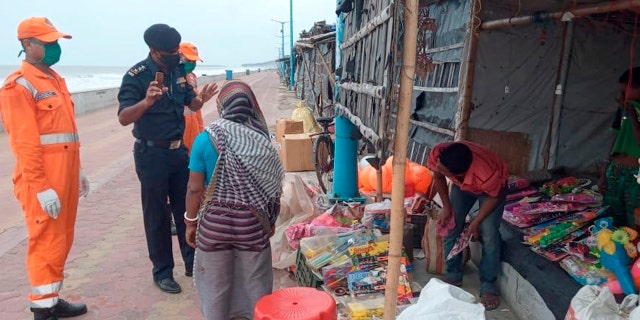 This photograph provided by India's National Disaster Response Force (NDRF) force shows NDRF personal warning people on the Bay of Bengal coast about Cyclone Amphan at Namkhana, South 24 Parganas, West Bengal, India, Tuesday, May 19, 2020.