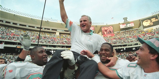 Miami Dolphins coach Don Shula is carried off the field by players Keith Sims (L) and Larry Webster (C) after Miami defeated Philadelphia 19-14 in Philadelphia November 14, 1993. This win made Shula the most successful coach in the league giving him his 325th career victory. (REUTERS/Gary Hershorn)