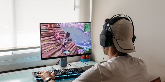 Teenager playing Fortnite video game on PC. Fortnite is an online multiplayer video game developed by Epic Games