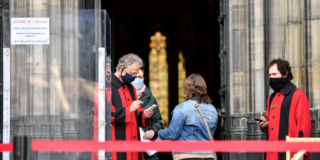 Believers arrive with online tickets for the first church service at Germany's famed Cologne Cathedral after coronavirus restrictions loosened in Cologne, Germany on Sunday. (AP Photo/Martin Meissner)