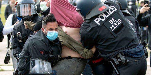 Des policiers arrêtent un homme lors d'une manifestation contre les restrictions et les mesures visant à empêcher la propagation du nouveau coronavirus à Berlin, en Allemagne, le samedi 16 mai 2020. 