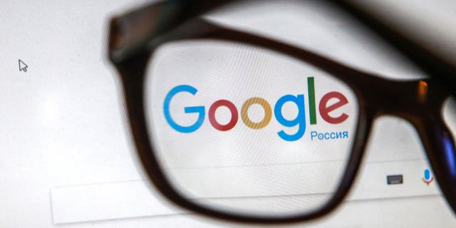 Glasses on a computer screen showing the logo and search box of the Google search engine in Russian. 