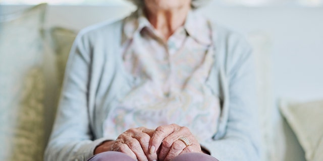 A senior woman sits on the sofa alone in the living room of a nursing home. For some people, the aging process moves more quickly than for others, which is referred to as "accelerated aging."