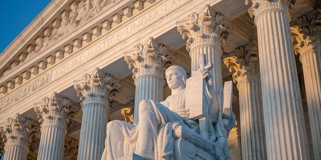 Sunset glow illuminated statue and colonnade of U.S. Supreme Court in Washington, D.C.