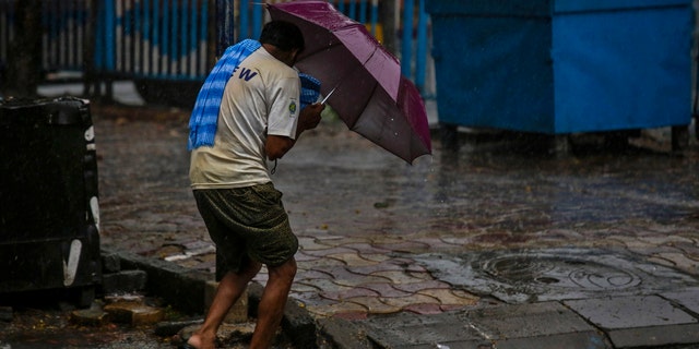 A man struggles to hold his umbrella and walk against high wind in Kolkata, India, May 20, 2020.