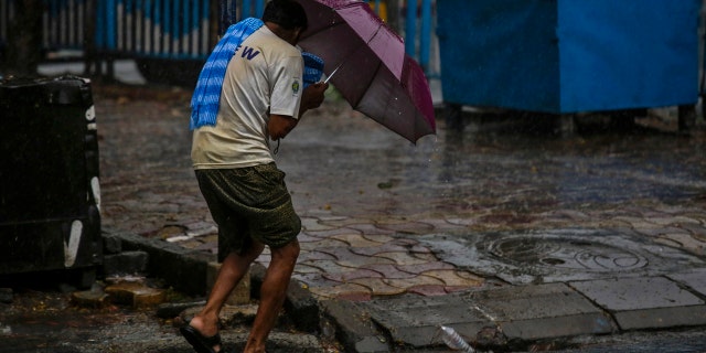 A man struggles to hold his umbrella and walk against high wind in Kolkata, India, May 20, 2020.