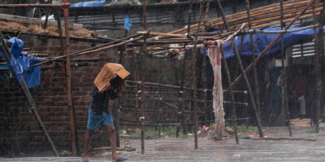 A man covers him head with a box and walks in the rain ahead of Cyclone Amphan landfall, at Bhadrak district, in the eastern Indian state of Orissa, May 20, 2020.