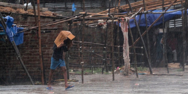 A man covers him head with a box and walks in the rain ahead of Cyclone Amphan landfall, at Bhadrak district, in the eastern Indian state of Orissa, May 20, 2020.