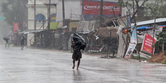 People walk with umbrellas in the rain ahead of Cyclone Amphan landfall, at Bhadrak district, in the eastern Indian state of Orissa, May 20, 2020.