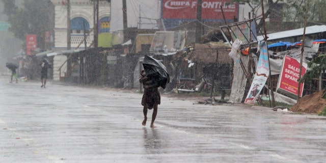 People walk with umbrellas in the rain ahead of Cyclone Amphan landfall, at Bhadrak district, in the eastern Indian state of Orissa, May 20, 2020.