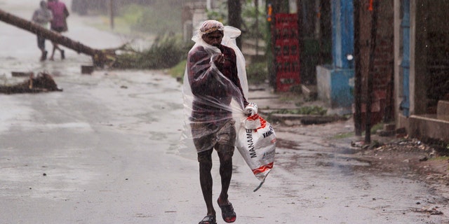 A man covers himself with a plastic sheet and walks in the rain ahead of Cyclone Amphan landfall, at Bhadrak district, in the eastern Indian state of Orissa, May 20, 2020.