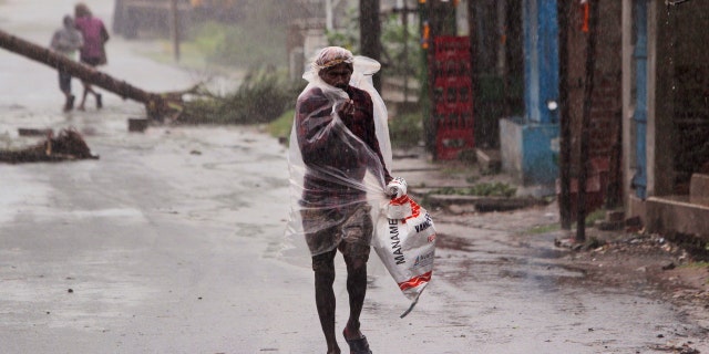 A man covers himself with a plastic sheet and walks in the rain ahead of Cyclone Amphan landfall, at Bhadrak district, in the eastern Indian state of Orissa, May 20, 2020.