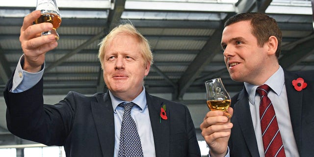 Junior British government minister Douglas Ross, right, has quit over Johnson’s failure to fire his top aide, Dominic Cummings, for allegedly breaching COVID-19 coronavirus lockdown rules. (Stefan Rousseau / PA via AP)