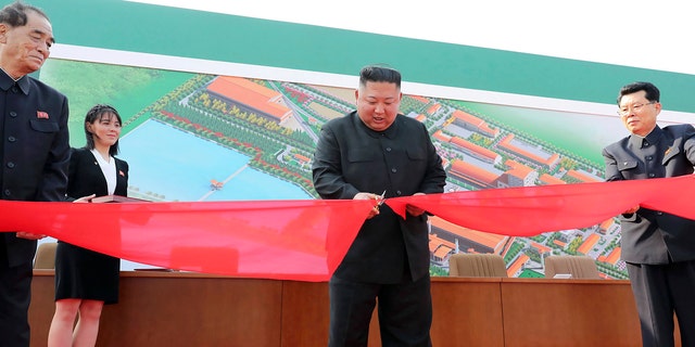 In this Friday, May 1, 2020, photo provided by the North Korean government, North Korean leader Kim Jong Un, center, cuts a tape, watched by his sister Kim Yo Jong, during his visit to a fertilizer factory in Sunchon, South Pyongan province, near Pyongyang, North Korea.