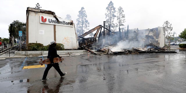 A man passing the burning UnionBank building on Sunday. (AP Photo/Gregory Bull)