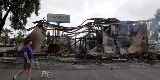 A man passing the Chase bank burned in the riots. (AP Photo/Gregory Bull)