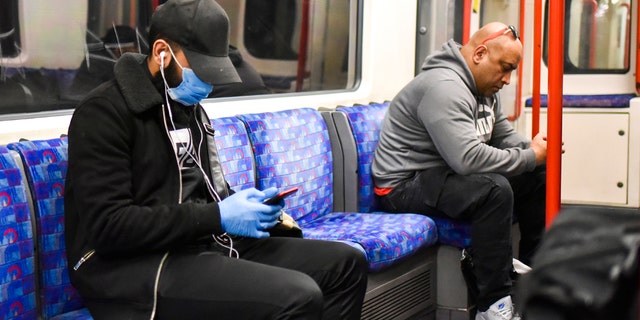 A man sits on a London underground train wearing a protective mask, in London, Tuesday, May 12, 2020. Britain's Prime Minister Boris Johnson announced Sunday limited changes to the national lockdown to limit the spread of the COVID-19 coronavirus.