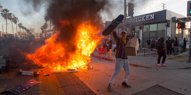A protester shouts in front of a fire during a protest over the death of George Floyd, a handcuffed black man in police custody in Minneapolis, in Los Angeles, Saturday, May 30, 2020.