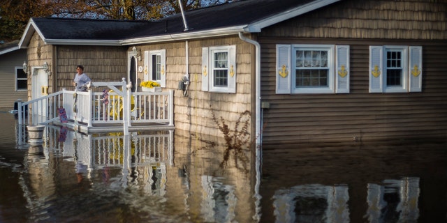 Carol Ouellette stands on her front porch, surrounded by floodwater, Tuesday, May 19, 2020 in Beaverton, Mich.