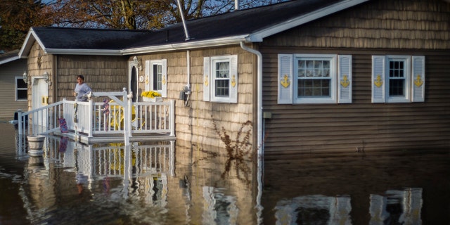 Carol Ouellette stands on her front porch, surrounded by floodwater, Tuesday, May 19, 2020 in Beaverton, Mich.