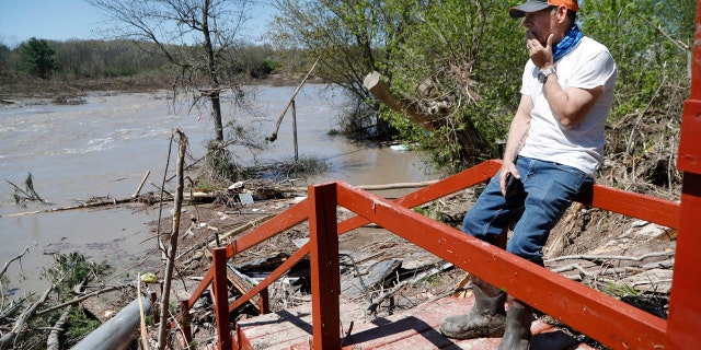 Dan Dionne looks over his former deck outside his home, May 20, in Edenville, Mich.