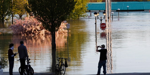 People photograph the floodwaters of the Tittabawassee River that encroached on downtown Midland, Mich., May 20.