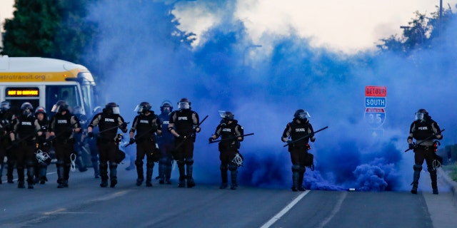 Police in riot gear prepares to advance on protesters, Saturday, May 30, 2020, in Minneapolis.
