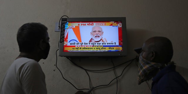 Indians watch a televised address to the nation by Prime Minister Narendra Modi in Hyderabad, India, on Tuesday. Modi announced that the government will spend the equivalent of nearly 10% of the country's GDP on a coronavirus virus economic relief package designed to make the world's second most populous nation more self reliant. (AP)
