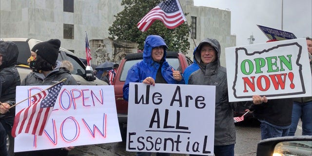 Demonstrators hold signs protesting Gov. Kate Brown's executive order that shut down much of the state's economy and imposed social distancing in her effort to stem the spread of the coronavirus. (AP Photo/Andrew Selsky)