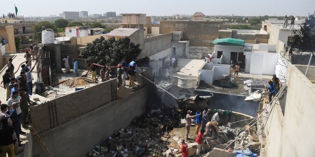 Rescue workers spray water on the part of a Pakistan International Airlines aircraft after it crashed at a residential area in Karachi on May 22, 2020.